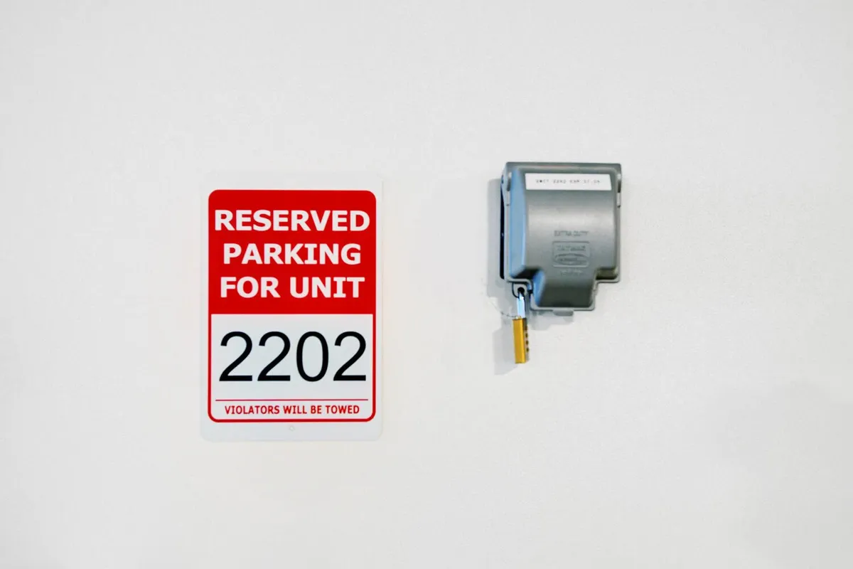This image shows a 'Reserved parking' sign and a parking meter within a garage space, conveying a sense of entry and arrival, and providing utilitarian context to the property. There are no visible signs of pets or animals, reinforcing the theme of a controlled and clean environment.