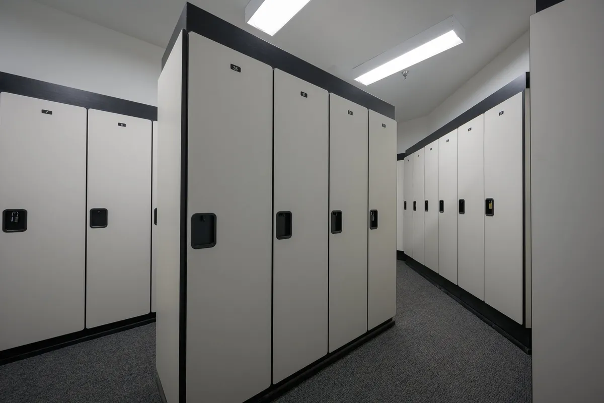 A well-lit, organized locker area with multiple lockers, clean flooring, and modern fixtures. The space is functional and orderly, offering secure storage for sports gear and personal items.